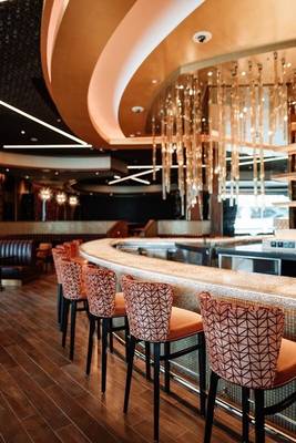 Barbereich im Hilton Dubai Palm Jumeirah mit modernen Stühlen und hängenden Kristallen.