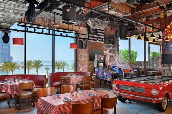 Innenbereich des Restaurants des Hilton Dubai Palm Jumeirah mit roten Bänken und Tischen, Blick auf das Meer.