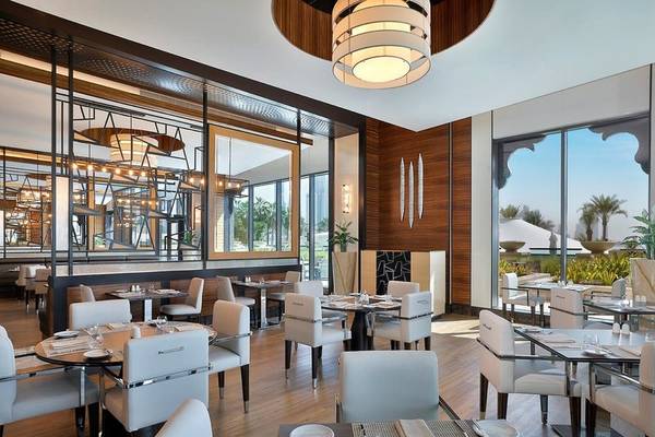 Innenansicht des Restaurants im Hilton Dubai Palm Jumeirah mit modernen Möbeln und großen Fenstern.