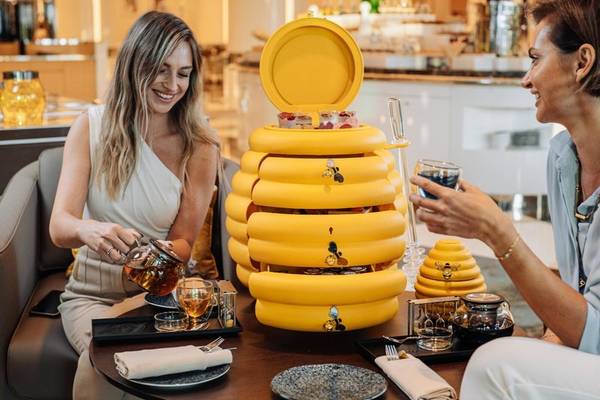Zwei Frauen genießen Tee am Tisch im Hilton Dubai Palm Jumeirah mit einer gelben Honigwabe.