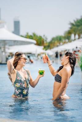 Zwei Frauen trinken Cocktails im Pool des Hilton Dubai Palm Jumeirah.