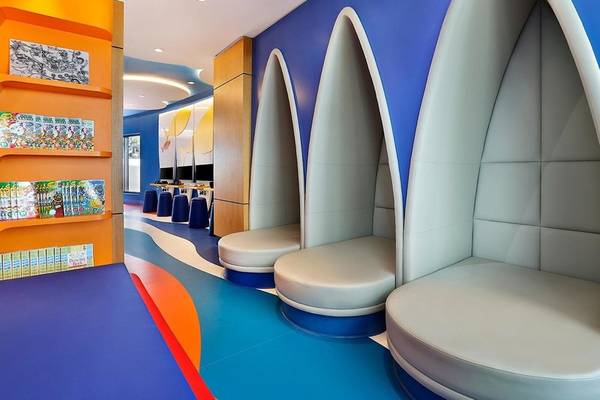 Der Kinderbereich im Hilton Dubai Palm Jumeirah mit blauen und orangefarbenen Wänden, Bücherregalen und Sitznischen.