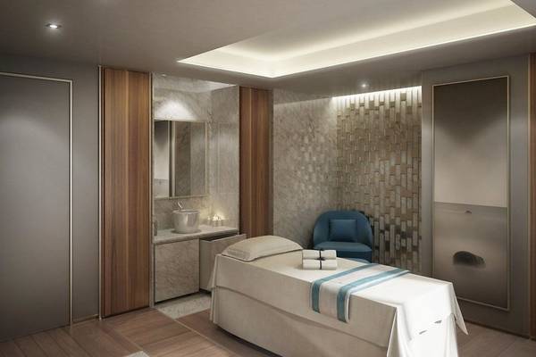 Spa-Behandlungsraum im Hilton Dubai Palm Jumeirah mit weißem Bett, blauem Stuhl und Marmorwand.