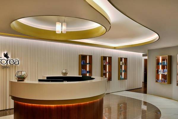Rezeption im Spa des Hilton Dubai Palm Jumeirah mit modernem Design und beleuchteten Regalen.