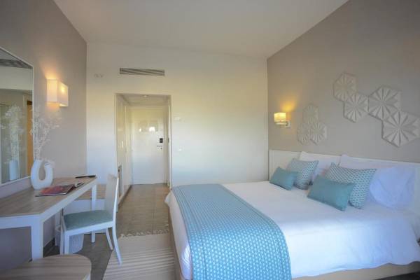 Innenansicht eines Hotelzimmers im Nozha Beach & Spa Hotel mit einem Bett, Schreibtisch und Stuhl.