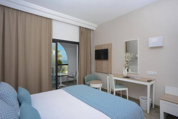 Innenansicht eines Hotelzimmers im Nozha Beach & Spa mit Bett, Schreibtisch und Meerblick.