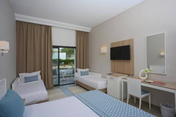 Hotelzimmer von Nozha Beach & Spa mit drei Betten, Schreibtisch und Fernseher.