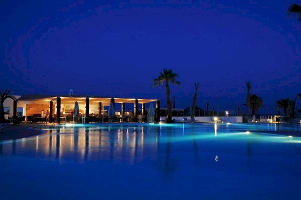 Ein Swimmingpool des Nozha Beach & Spa Hotels bei Nacht mit blauem Wasser und Beleuchtung.