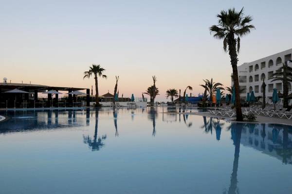 Außenpool des Nozha Beach & Spa Hotels bei Sonnenuntergang mit Palmen und Liegestühlen
