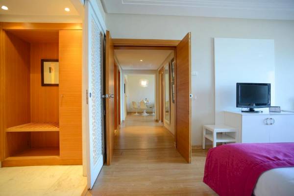 Innenansicht eines Hotelzimmers im Nozha Beach & Spa Hotel mit offenem Eingang, Fernseher, Schrank und Flur