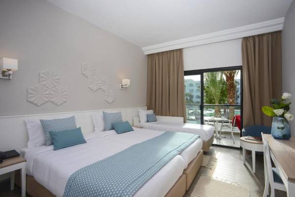 Doppelbettzimmer im Nozha Beach & Spa Hotel mit Blick auf den Pool.