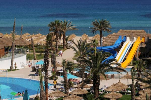 Aussenbereich des Nozha Beach & Spa Hotels mit Pools, Rutschen und Sonnenschirmen.