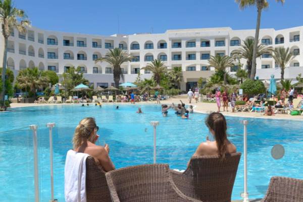 Zwei Frauen sitzen neben dem Pool im Nozha Beach & Spa Hotel und beobachten die Gäste.