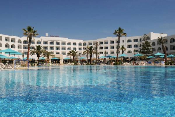 Poolbereich des Nozha Beach & Spa Hotels mit weißen Gebäuden und vielen Palmen.