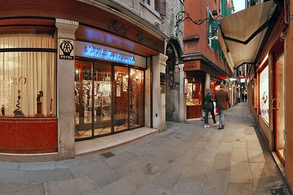 Das Hotel Montecarlo in Venedig, mit zwei Gästen, die die Gasse entlanggehen.