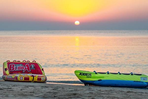 Sonnenuntergang am Strand mit einem Jobe Boot und einem Super Bubba Boot auf dem Sand.