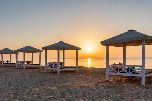 Vier weiße Zelte am Strand des Sealine Beach, A Murwab Resort bei Sonnenuntergang.