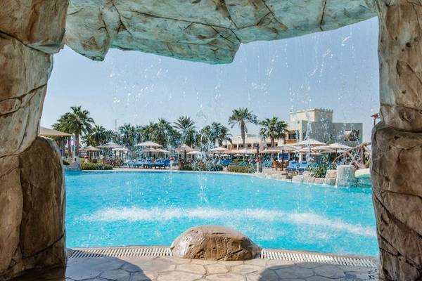 Blick auf den Pool im Sealine Beach, A Murwab Resort mit Wasserfall und Palmen