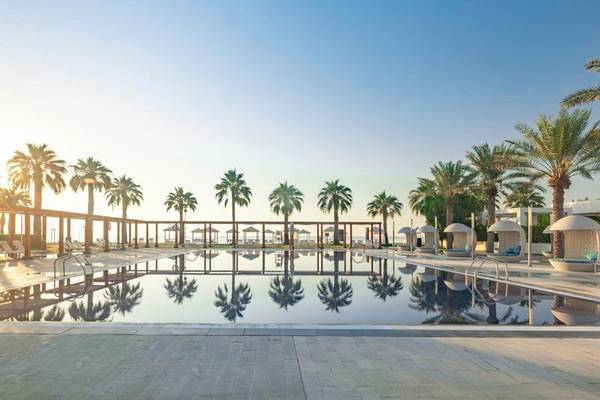 Poolbereich im Sealine Beach, A Murwab Resort mit Palmen und Loungebereichen