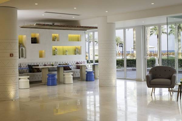 Lobby im Sealine Beach, A Murwab Resort mit Sitzgelegenheiten und Glastüren zum Meer.