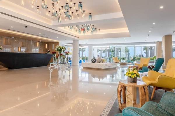 Empfangsbereich des Sealine Beach, A Murwab Resort mit hellen Farben, modernen Möbeln und einem großen Kronleuchter.