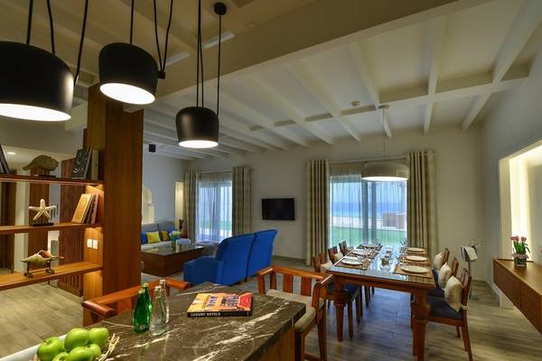 Innenbereich des Sealine Beach, A Murwab Resort mit Esstisch, Couch, Fernseher und Fenstern.