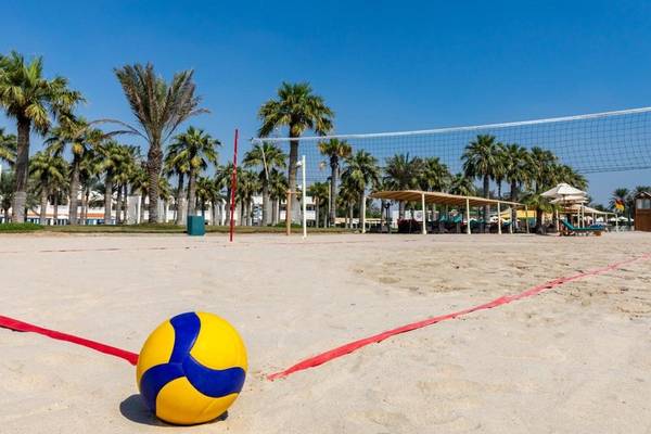 Volleyballplatz im Hotel Sealine Beach, A Murwab Resort mit Netz und Ball auf dem Sand.