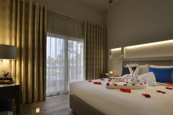 Hotelzimmer im Sealine Beach, A Murwab Resort mit Blumenarrangement und Kerzen auf dem Bett.