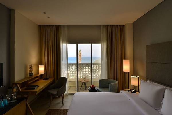 Zimmer im Sealine Beach, A Murwab Resort mit Blick auf das Meer und Palmen
