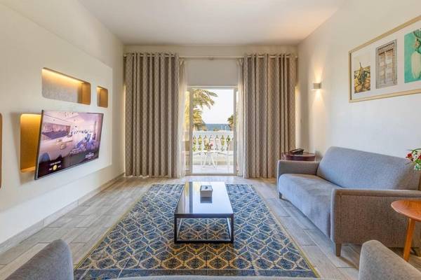 Wohnzimmer im Sealine Beach, A Murwab Resort mit Fernseher, Couch, Tisch und Balkon