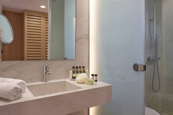 Badezimmer im Pilot Beach Resort mit Marmorwaschbecken, Spiegel und Duschkabine.
