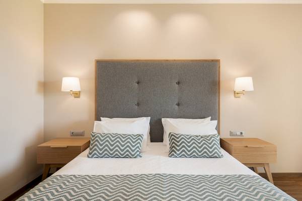 Schlafzimmer im Pilot Beach Resort mit Doppelbett, grauem Kopfteil und zwei Nachttischen.
