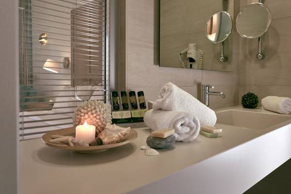 Badezimmer im Pilot Beach Resort mit heller Einrichtung, Handtüchern, Kerze und Föhn