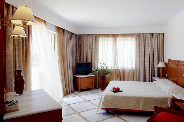 Hotelzimmer im Pilot Beach Resort mit Bett, Fernseher und Tischlampen.