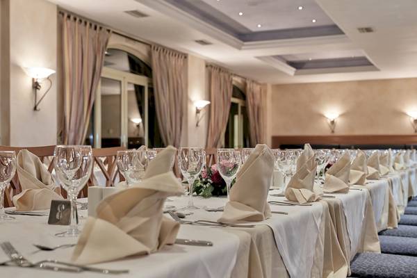 Ein elegantes Esszimmer im Pilot Beach Resort mit gepolsten Stühlen, gedeckten Tischen und Blumengestecken.