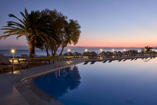 Pool am Abend im Pilot Beach Resort mit Loungestühlen und Palmen