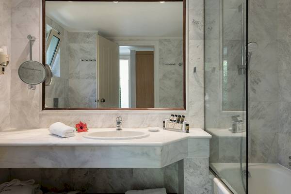 Badezimmer im Pilot Beach Resort mit großem Spiegel, Waschbecken und Badewanne.