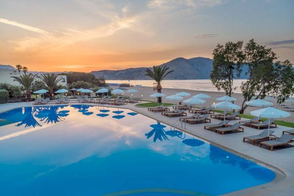 Sonnenuntergang am Pool des Pilot Beach Resorts mit Liegestühlen und Sonnenschirmen.