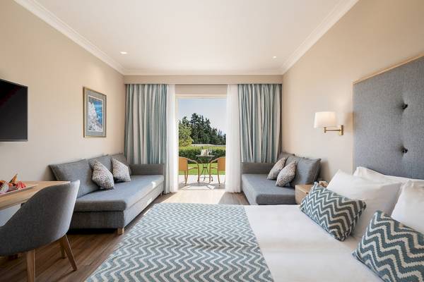 Hotelzimmer im Pilot Beach Resort mit großem Bett, Sofa, Tisch und Terrassenzugang.