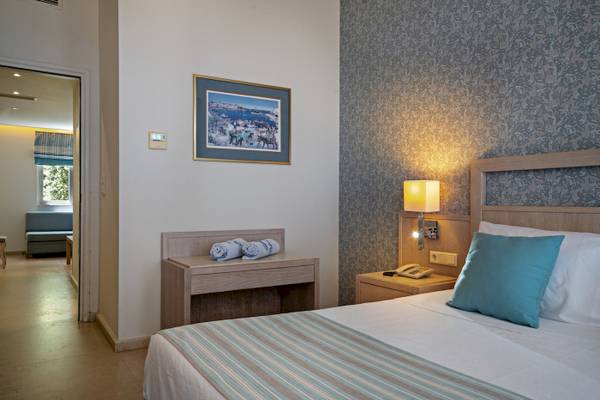 Innenansicht eines Schlafzimmers im Pilot Beach Resort mit Bett, Nachttisch und Lampe.