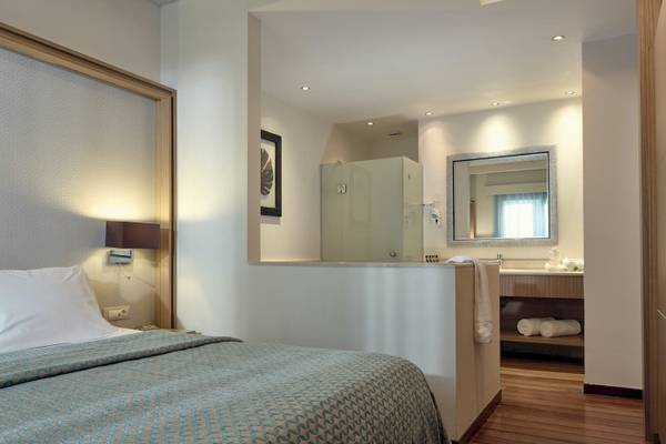 Innenansicht eines Hotelzimmers im Pilot Beach Resort mit Bett, Lampe und Badezimmerbereich.