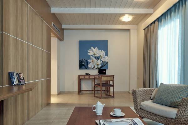 Innenansicht eines Zimmers im Pilot Beach Resort Hotel mit Schreibtisch, Laptop, Gemälde und Wohnzimmermöbeln.