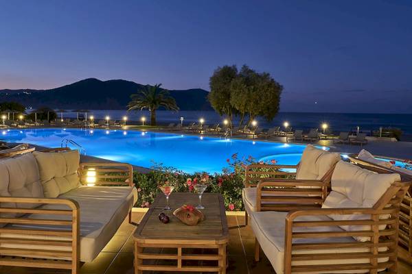 Aussenbereich des Pilot Beach Resorts bei Nacht mit Swimmingpool, Loungemöbeln und Blick auf das Meer.