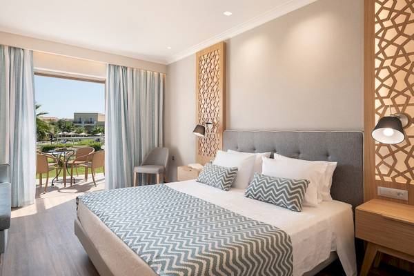 Schlafzimmer im Pilot Beach Resort mit Blick auf einen Balkon und Gartenmöbel.