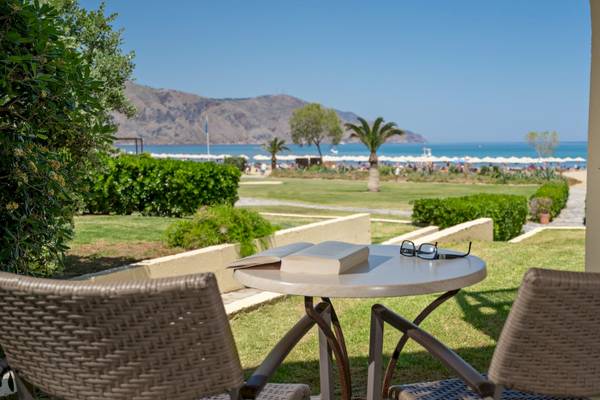 Blick vom Pilot Beach Resort auf den Garten mit Tisch, Buch und Sonnenbrille