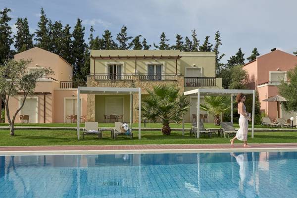 Außenansicht des Pilot Beach Resorts mit Swimmingpool, Sonnenliegen und Gebäuden im Hintergrund.