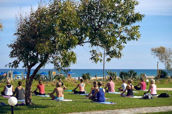 Gruppe von Menschen, die Yoga auf dem Rasen im Freien im Pilot Beach Resort machen