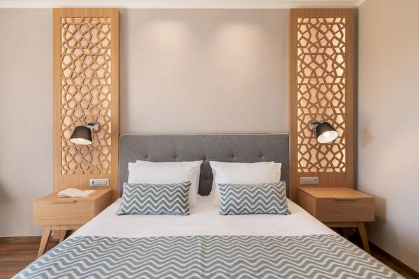 Schlafzimmer im Pilot Beach Resort mit zwei Nachttischen, Bett und dekorativen Wandpaneelen.