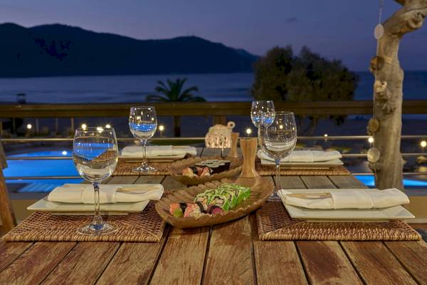 Terrassentisch im Pilot Beach Resort mit Blick auf den Pool und das Meer bei Nacht.