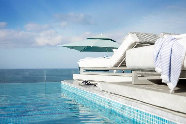 Außenpool des Mare Paphos Hotels mit Lounge-Sesseln und Blick aufs Meer.